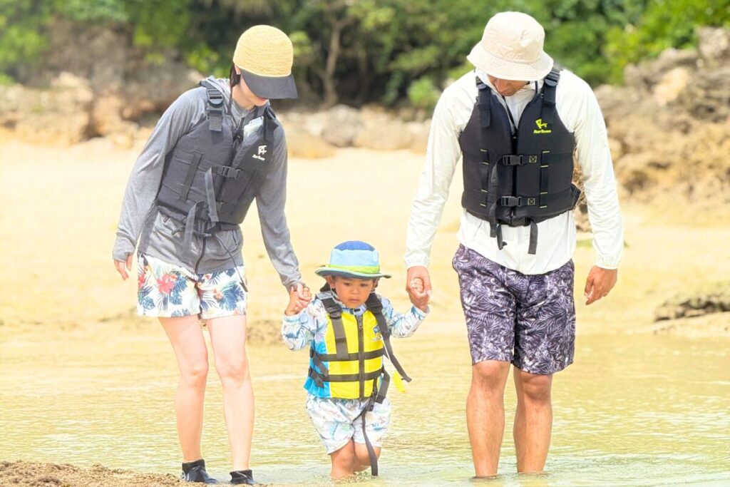 手をつなぎながら宮古島の海辺を歩く家族