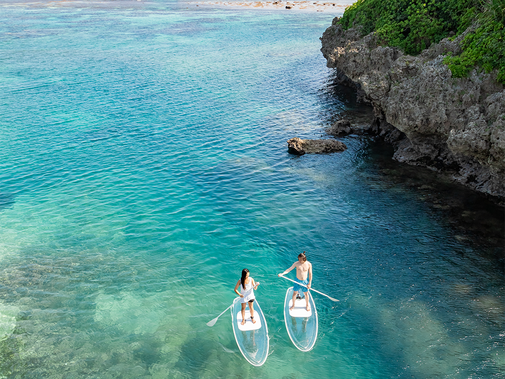 宮古島で透明な海の上でクリアサップを楽しむカップルの空撮です