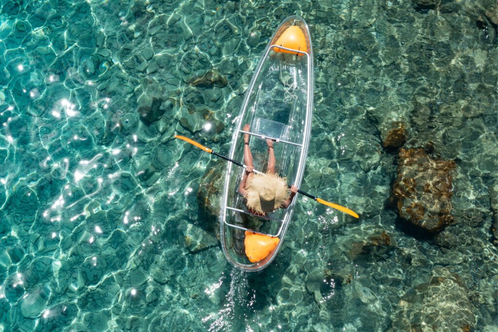 ドローンに撮影された、透明な宮古島の海でクリアカヤックを楽しむ女性