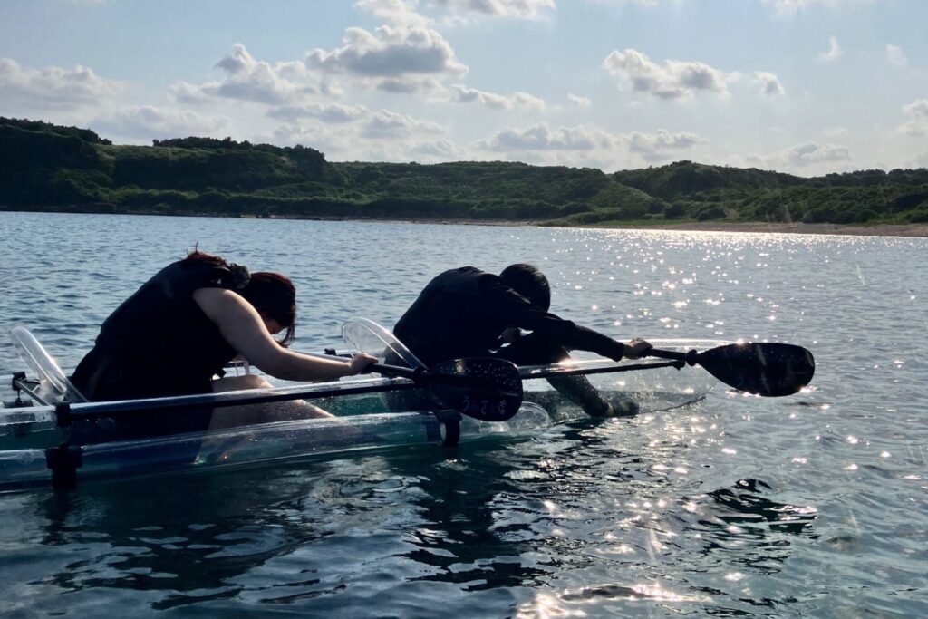 宮古島でクリアカヤックを楽しむ男女、水中の魚に夢中で下を向いてる