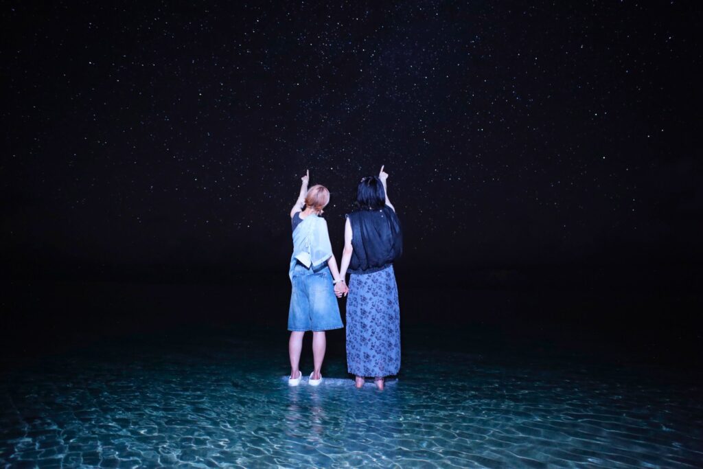 海の上に浮かぶ女性二人と宮古島の満点の星空