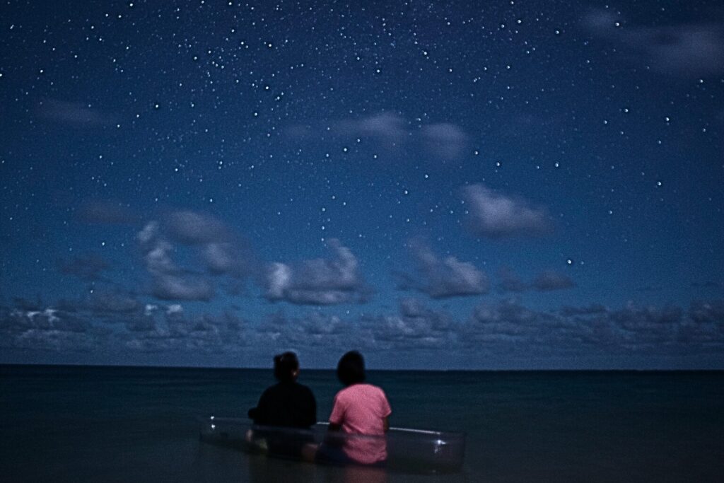 星空と夜の海でクリアカヤックに乗っている女性二人