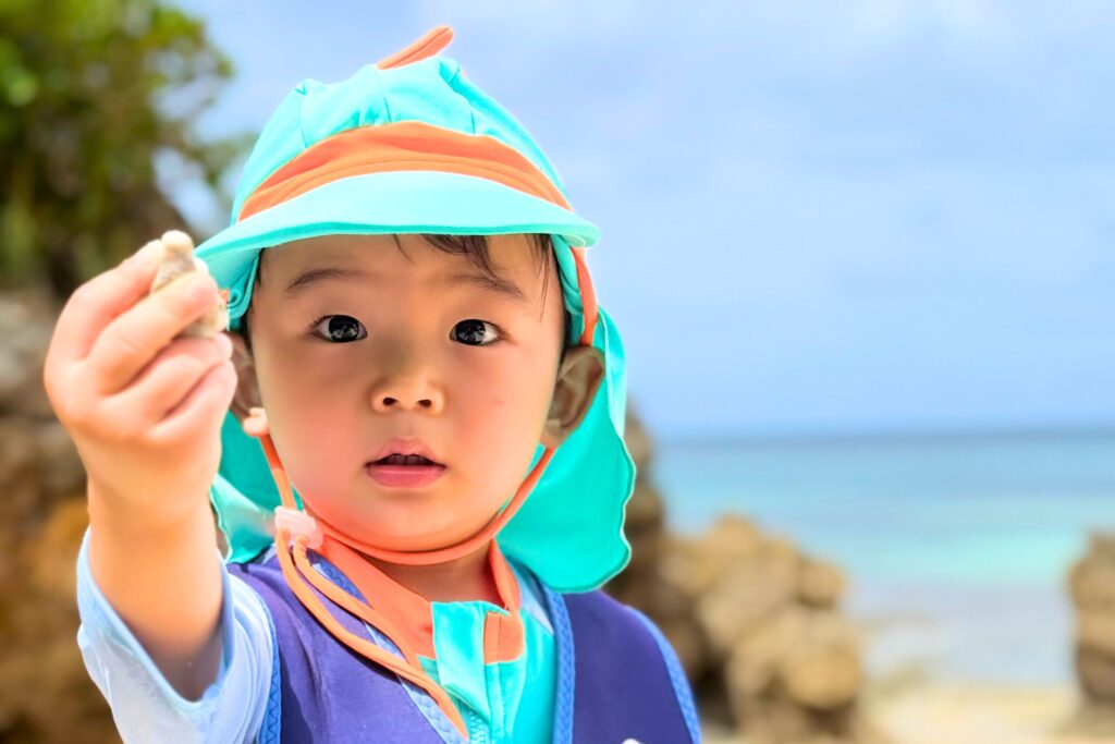 恐竜の服を着た可愛い子供が宮古島の浜辺で遊んでいる