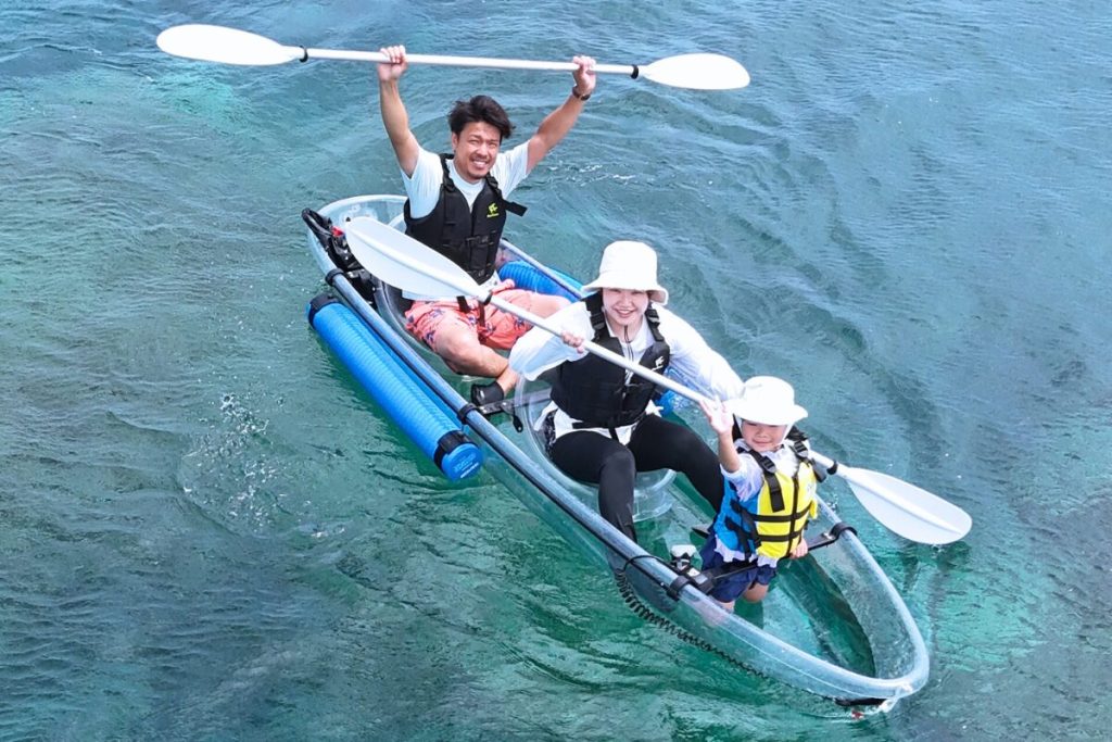 家族みんなでカヤックにのり上空のカメラに向かって笑顔