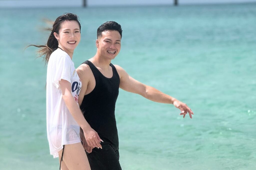 海をバックに夫婦が歩く 髪をなびかせながら満面の笑顔