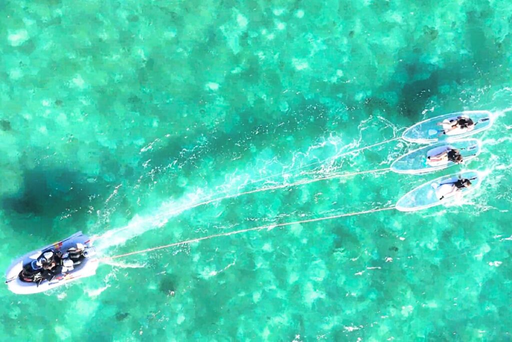 サップをボートで牽引 エメラルドグリーンの海に白波が映えている