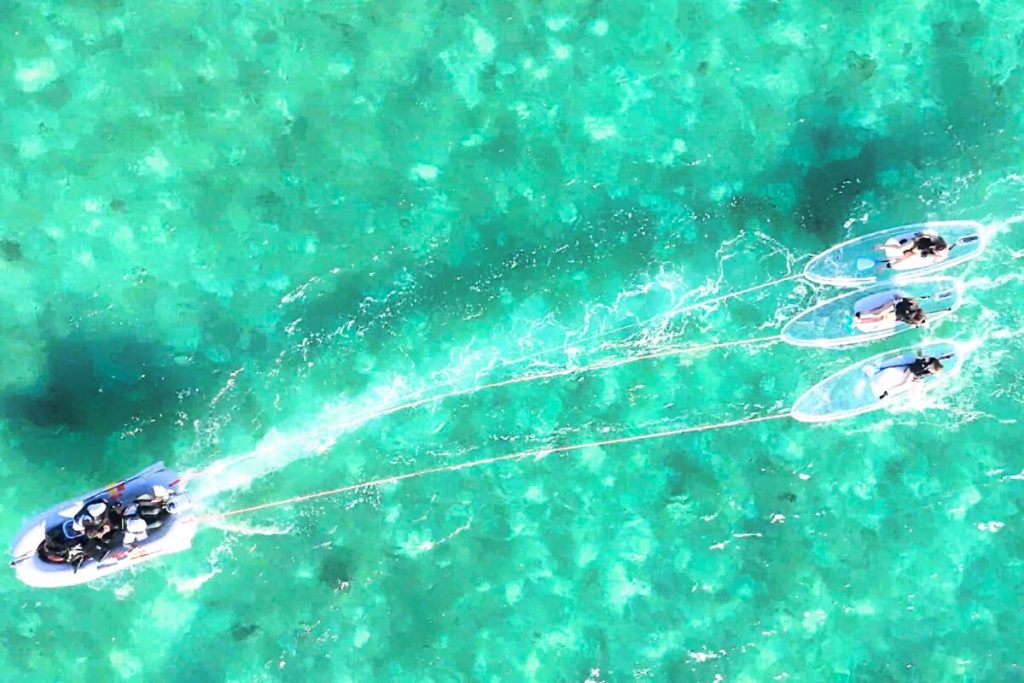 サップをボートで牽引 エメラルドグリーンの海に白波が映えている