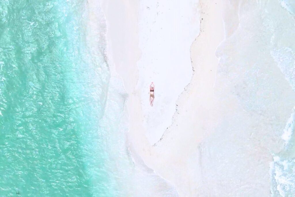ユニの浜の先端で寝っ転がっているショット 露出しているユニの浜の両サイドから波が押し寄せる