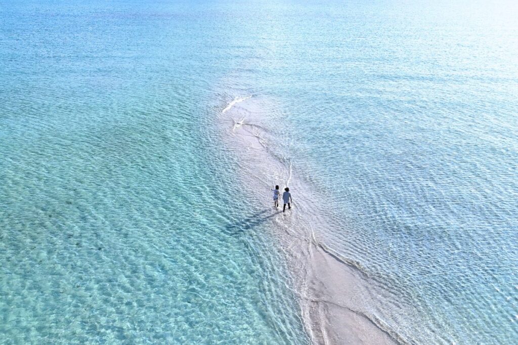 少しだけ露出したユニの浜を歩く二人