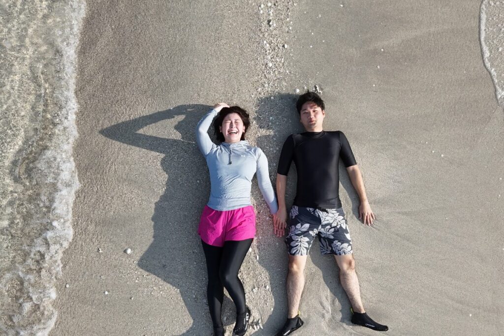 ユニの浜に寝っ転がってニッコニコの笑顔を向けてくれてる二人