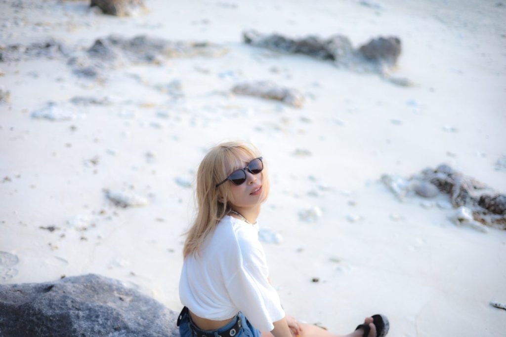 白い砂浜に座ってカメラに向かって振り向いた一周をパシャリ