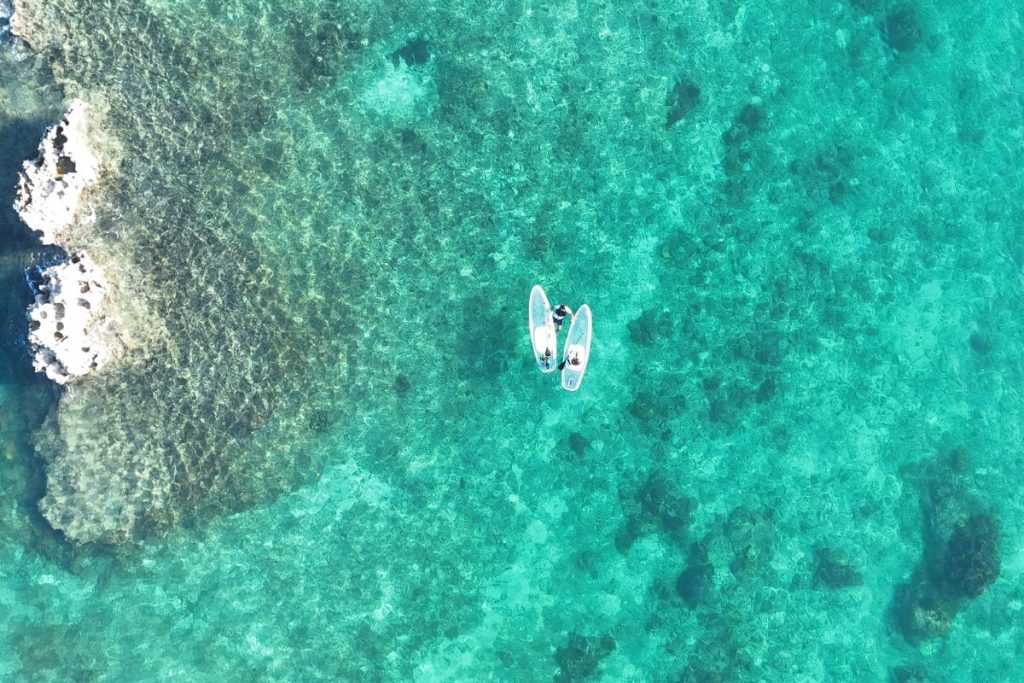 宮古島の透明度の高い海を、2台のクリアSUPで進む様子をドローンで真上から撮影したサンセットツアーの写真