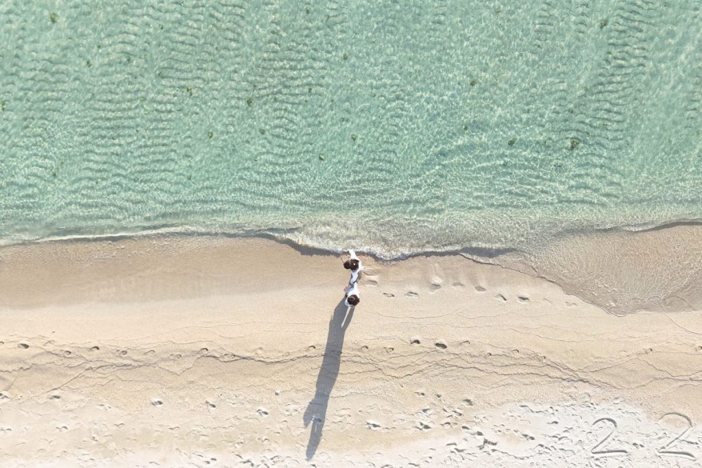 宮古島・ユニの浜の白い砂浜を上空から撮影！透明な海と波打ち際、長く伸びた影が印象的な女子旅の一枚