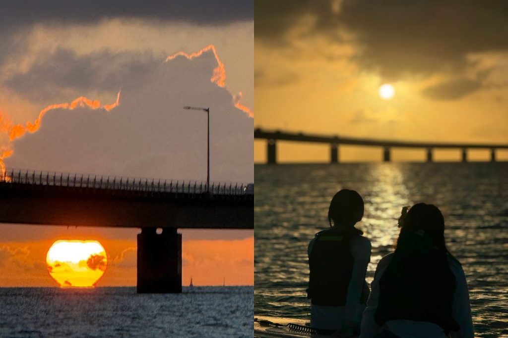 伊良部大橋の向こうに沈む夕陽と、海の上でサンセットを眺める女性二人のシルエット