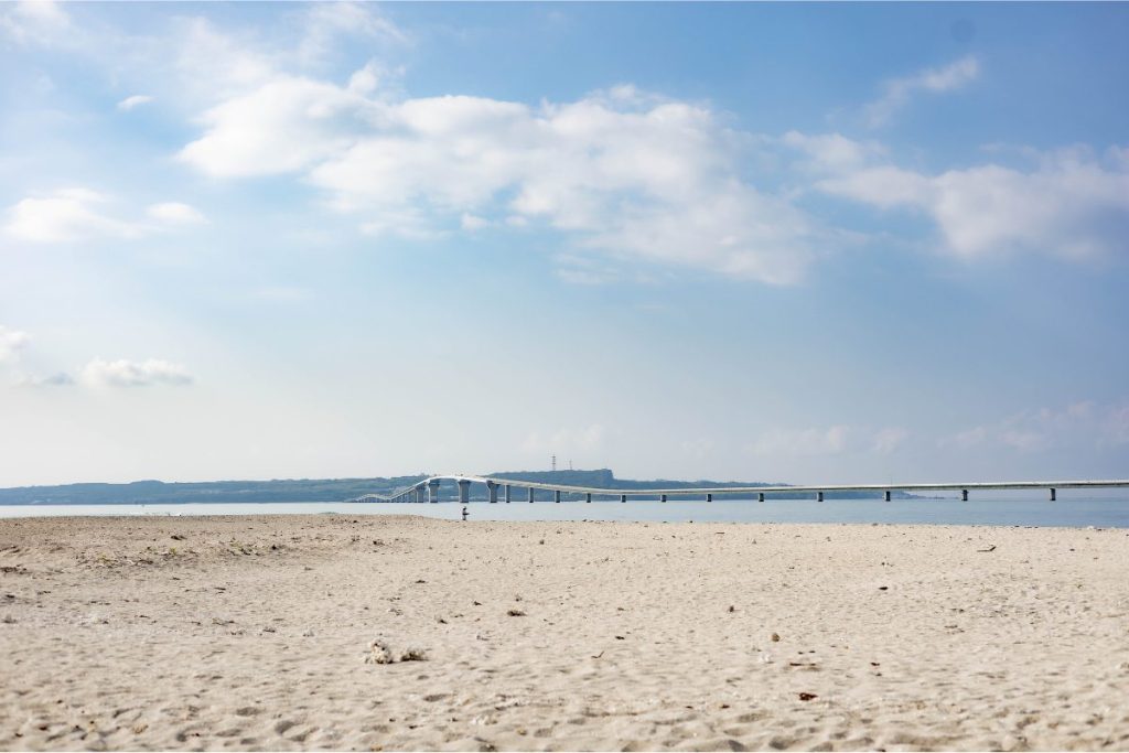 宮古島の青い海と白い砂浜、水平線に伸びる伊良部大橋を写した美しい風景